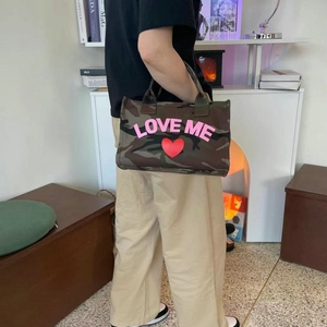 Detail of camouflage tote bag with pink LOVE ME print and sturdy carry handles