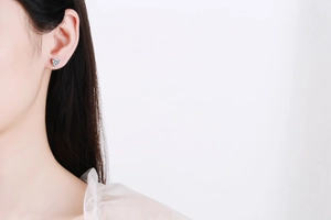 Close-up of heart-shaped light blue moissanite earring on a female model ear