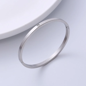 Brushed stainless steel bangle with square zircon inlay shown from a side angle