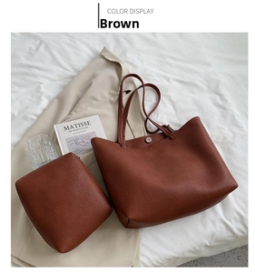 Detailed view of brown lychee-grain leather tote bag set on elegant white fabric