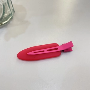 Close-up of matte pink dual-tone hair clip with metal spring mechanism on white surface