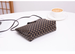 Detail of vintage brown crossbody bag with geometric pattern on a white table