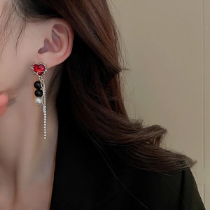 Close-up of dangling heart earrings with long rhinestone tassels on elegant model