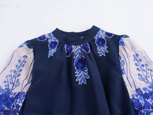 Detail of elegant floral print chiffon dress with navy blue bodice and sheer cream sleeves
