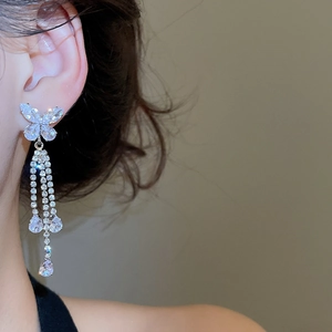 Close-up of silver butterfly tassel earrings with sparkling cubic zirconia on a model