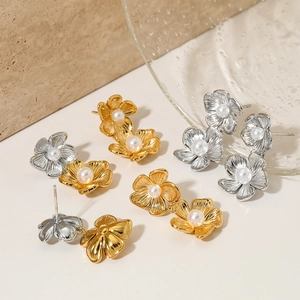 Set aus goldenen und silbernen Blumenperlenohrringen auf strukturierter Steinfläche