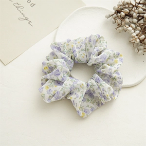 Detailed macro view of chiffon floral scrunchie with soft pastel tie-dye flower patterns