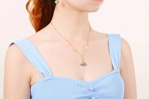 Close-up of golden fan-shaped necklace and earrings set with crystal inlay on a model