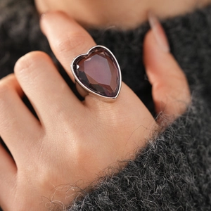 Detailed view of silver ring featuring a large heart-shaped purple zircon on index finger