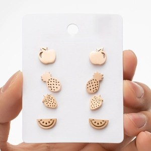 Close-up of four pairs of stainless steel fruit studs on a white display card