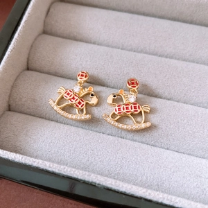 Macro shot of 18K gold plated rocking horse stud earrings with red enamel and zircons