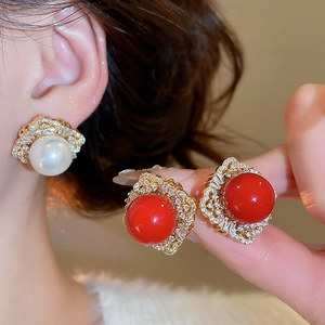 Close-up of vintage hollow gold earrings with pearls, zircons and intricate lace patterns