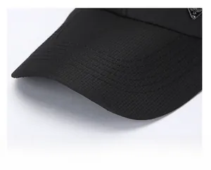 Macro view of black baseball cap brim with mesh texture and triangle metal logo