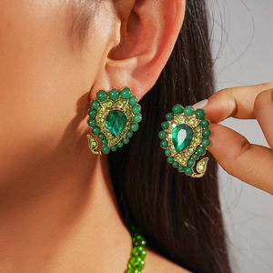 Dettaglio degli orecchini vintage a goccia verde con montatura dorata e strass