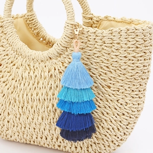 Ciondolo per borsa a nappe sfumate blu a cinque strati appeso a una borsa intrecciata