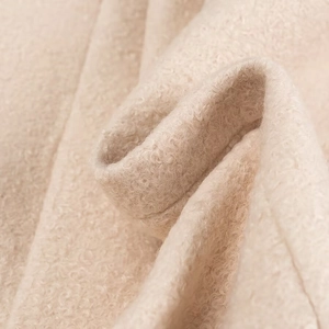 Dettaglio del tessuto bouclé beige di un cappotto lungo che mostra la trama arricciata