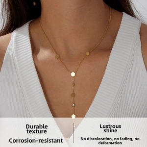 Close-up of gold-plated Y-necklace with flower charms and crystals on a female model