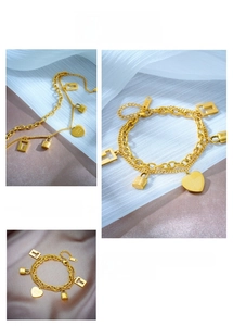 Macro detail of gold double-layer chain bracelet with heart, lock and square charms