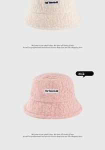 Detail view of pink and beige lamb wool bucket hats with embroidered letter patches