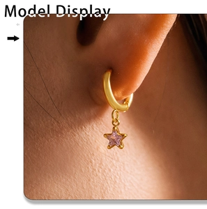 Macro shot of model wearing a gold hoop earring with a purple glass star pendant