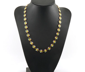 Detail of multi-colored enamel daisy flowers on a gold-plated stainless steel chain