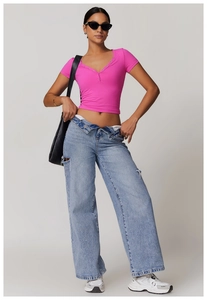 Detail of rose pink henley neck sports T-shirt with metal buttons and distressed jeans