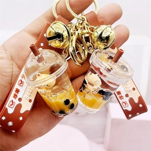 Close-up of pearl milk tea bear keychain with yellow liquid and brown wrist strap