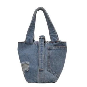 Washed blue denim bucket bag with distressed hole detail and vintage metal ring