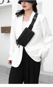 Close-up of black oxford cloth waist bag with double zippers worn by a model in white