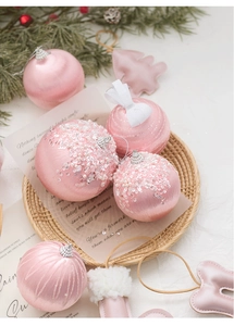 Macro detail of pink silk Christmas baubles with pearls and sequins in a woven tray