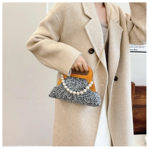 Detail of grey tweed evening bag with wooden handle and oversized pearl chain strap