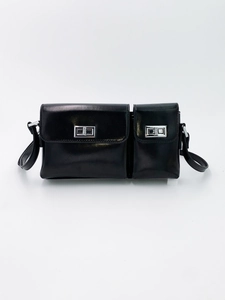 Front detail of black baguette bag featuring dual pockets and silver metal twist locks