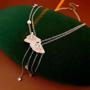 Close-up of pink fan-shaped pendants with sparkling zircon and pearls on velvet