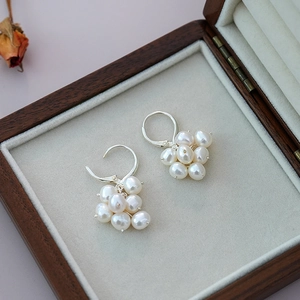Macro detail of grape-shaped freshwater pearl earrings on vintage wood jewelry box