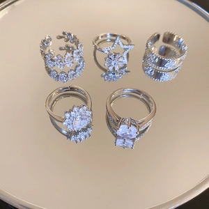 Macro detail of five silver snowflake zircon rings on mirror with elegant reflections