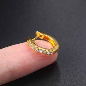 Close-up of a gold-plated ear cuff with micro-pave zircons held on a finger
