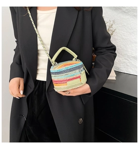 Dettaglio borsa in paglia intrecciata arcobaleno con manico in pelle verde e catenella