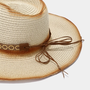 Détail du chapeau de paille avec bande en cuir marron et motifs hexagonaux dorés