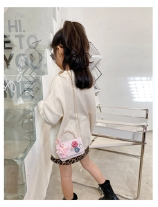 Pink tweed girls crossbody bag featuring pearl handle and cute rabbit charm on a child model