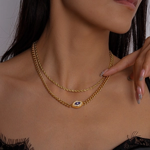 Macro shot of layered gold necklaces with evil eye pendant and cubic zirconia details