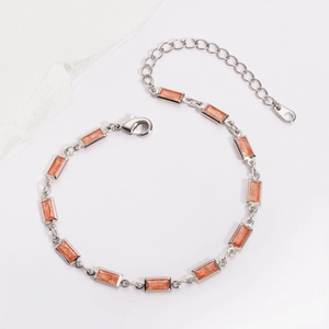 Détail du bracelet en chaîne argentée avec pierres orange rectangulaires et fermoir mousqueton