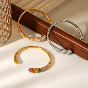 Detail of 18k gold and silver open bangles with pearls and rainbow crystals on a wooden stand