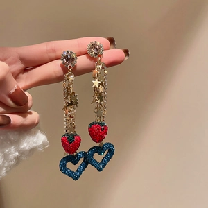 Detailed close-up of tassel earrings with star charms, red strawberry, and blue heart