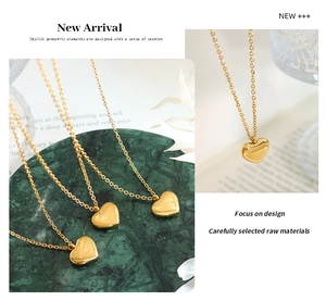 Detail of 18k gold plated heart pendant necklace on green marble and white petals