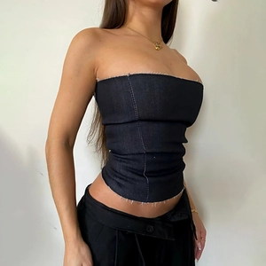 Détail macro du haut bustier en denim noir avec ourlet brut et double couture centrale