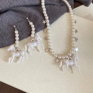 Parure de bijoux en perles avec pendentifs licorne colorés et étoiles sur plateau blanc