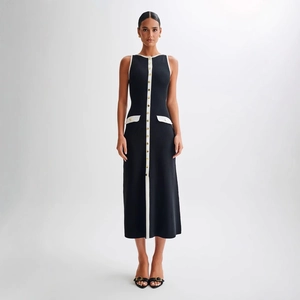 Détail de la robe noire en maille avec patte contrastée blanche et boutons dorés élégants