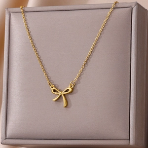 Macro detail of 18k gold butterfly bow pendant necklace on elegant jewelry box