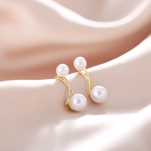 Macro shot of French vintage pearl earrings with gold crossed metal on silk background