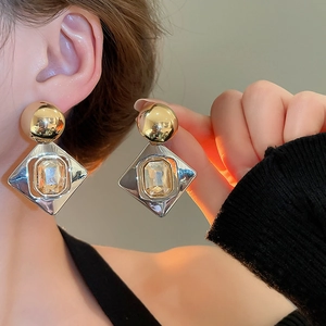Gros plan de boucles d'oreilles géométriques en losange avec finition or et argent